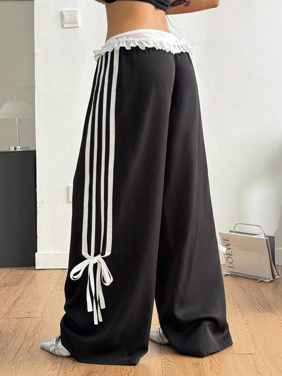 Women's black wide leg casual pants featuring a mid-rise drawstring waistband, contrast lace trim with bow detailing, and side stripes.