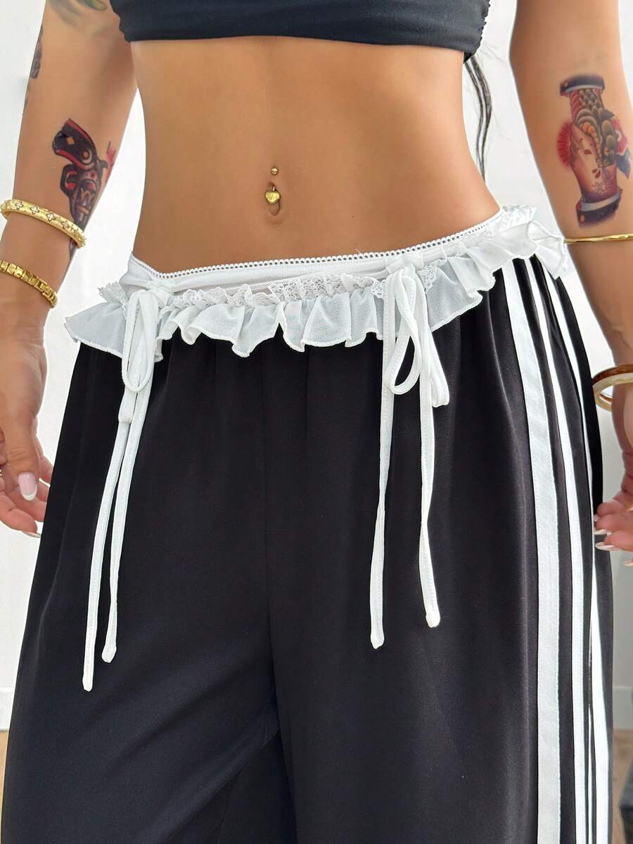 Women's black wide leg casual pants featuring a mid-rise drawstring waistband, contrast lace trim with bow detailing, and side stripes.