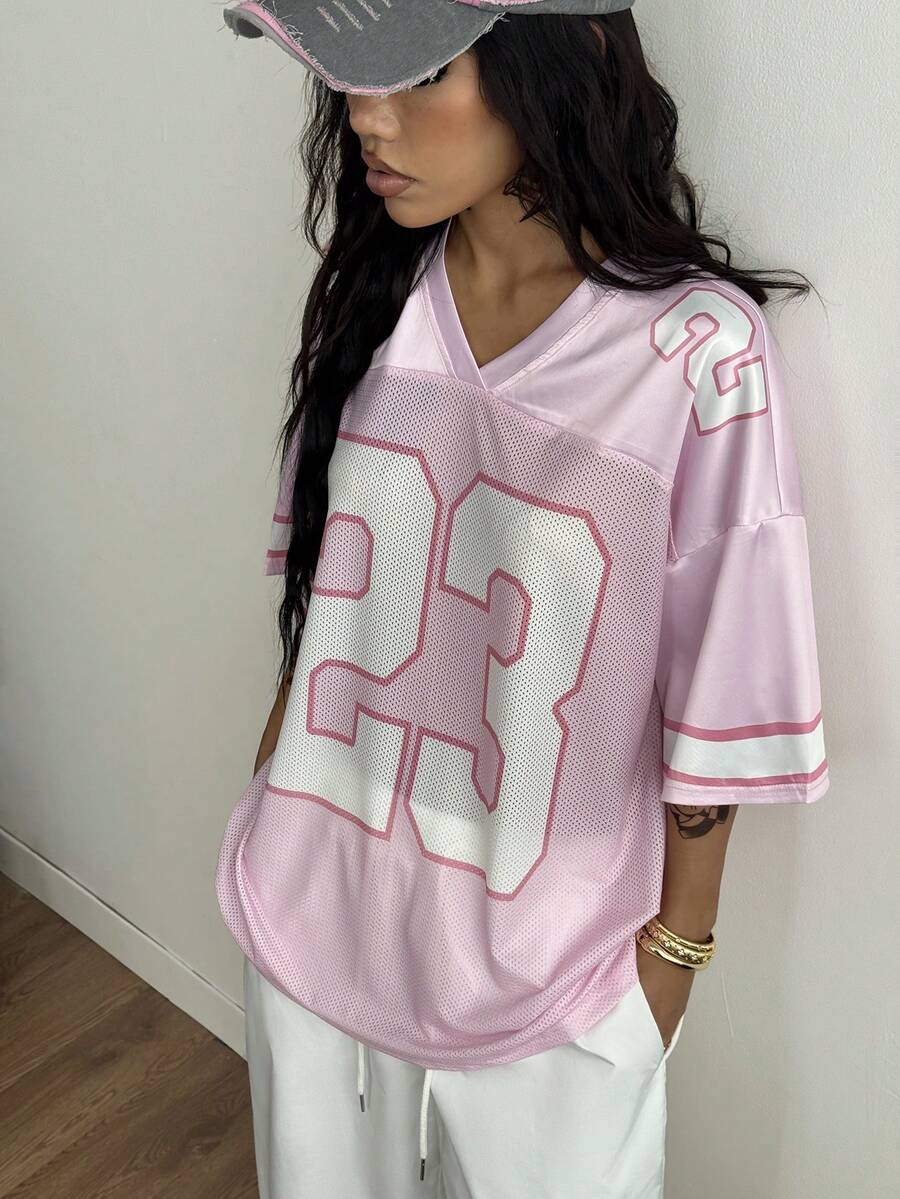 Oversized short-sleeve football jersey top featuring a V-neckline, contrast binding, and graphic number print.