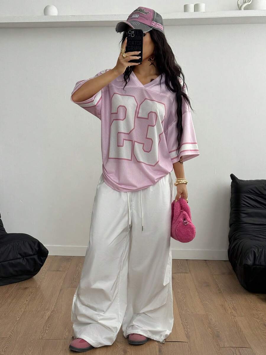 Oversized short-sleeve football jersey top featuring a V-neckline, contrast binding, and graphic number print.