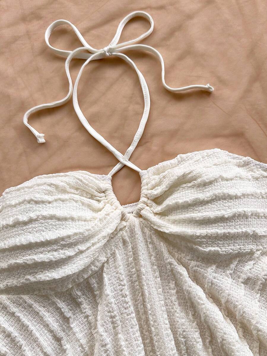 Women's textured V-neck halter tank top with backless knot detail, ruffle hem, and flared silhouette for casual beach and vacation wear.