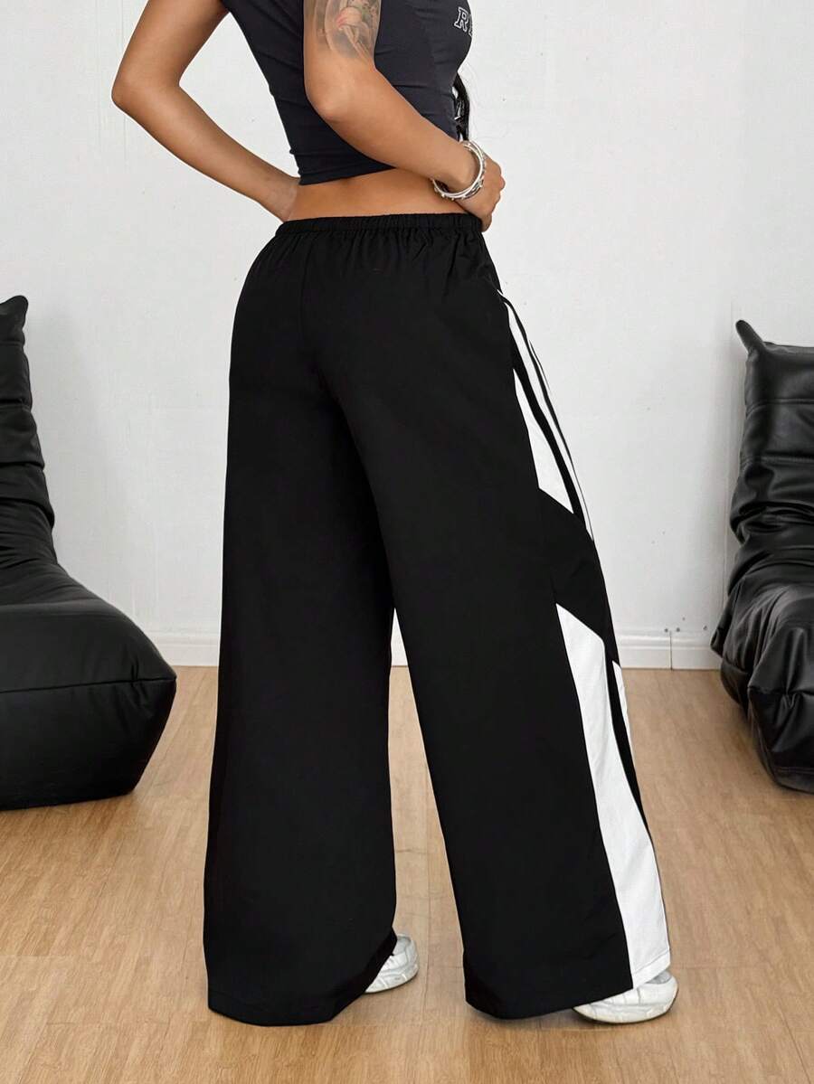 Women's wide leg parachute pants featuring an army green color-blocked design with side stripes and an adjustable drawstring waist.