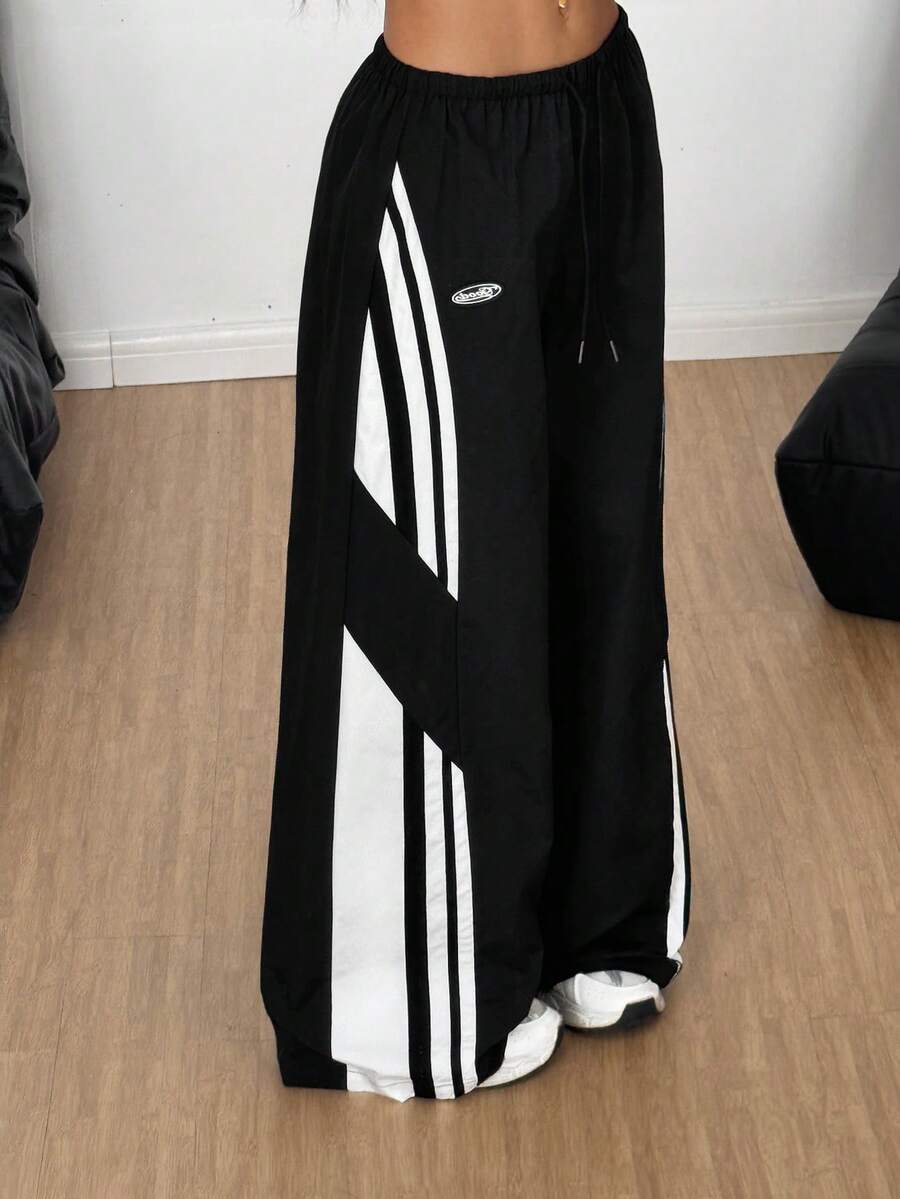 Women's wide leg parachute pants featuring an army green color-blocked design with side stripes and an adjustable drawstring waist.