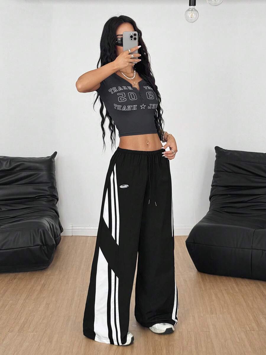 Women's wide leg parachute pants featuring an army green color-blocked design with side stripes and an adjustable drawstring waist.