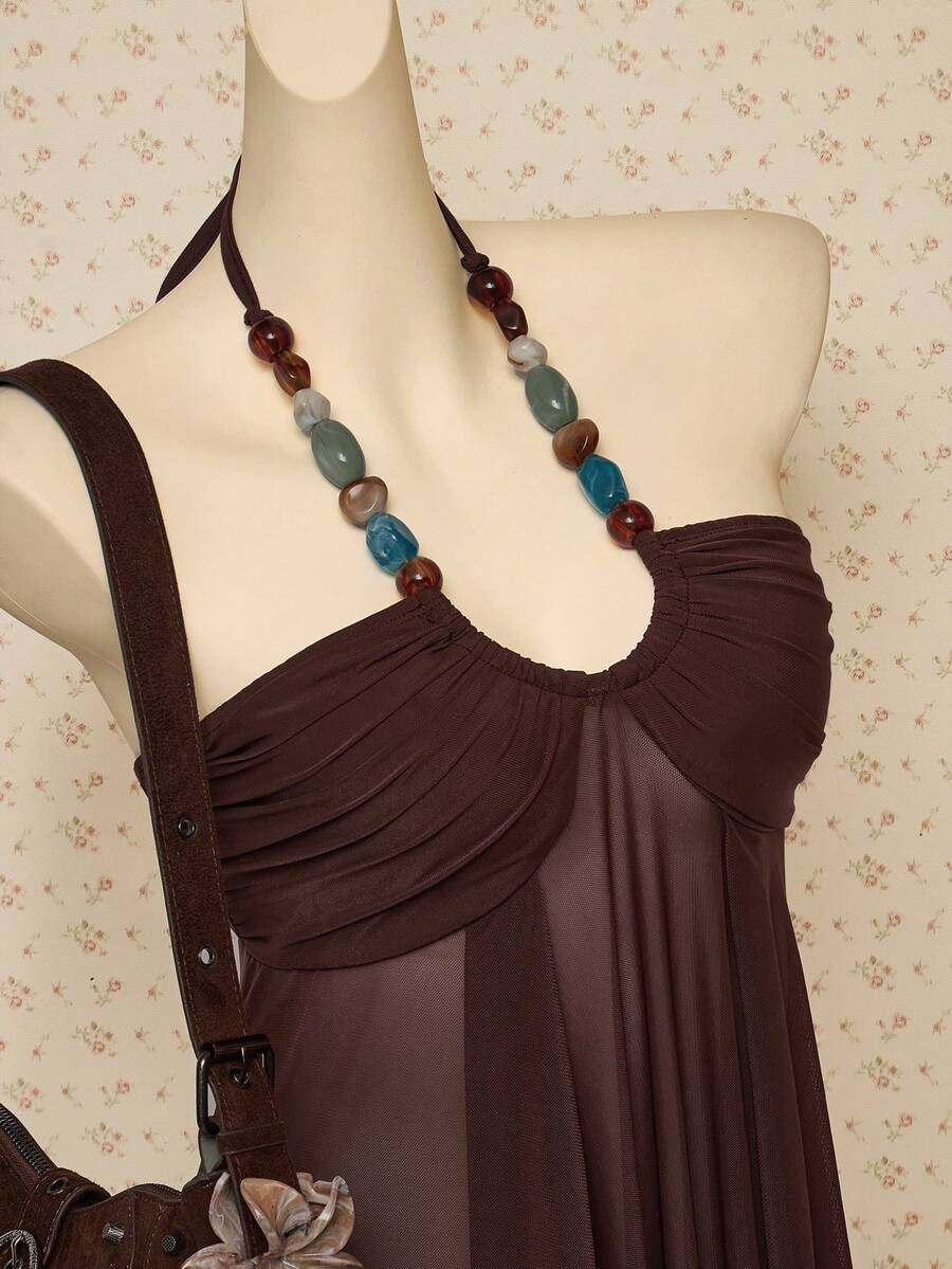 Women's boho halter mesh tank top with asymmetrical hem, semi-sheer finish, lined body, slim fit, and cold shoulder styling.