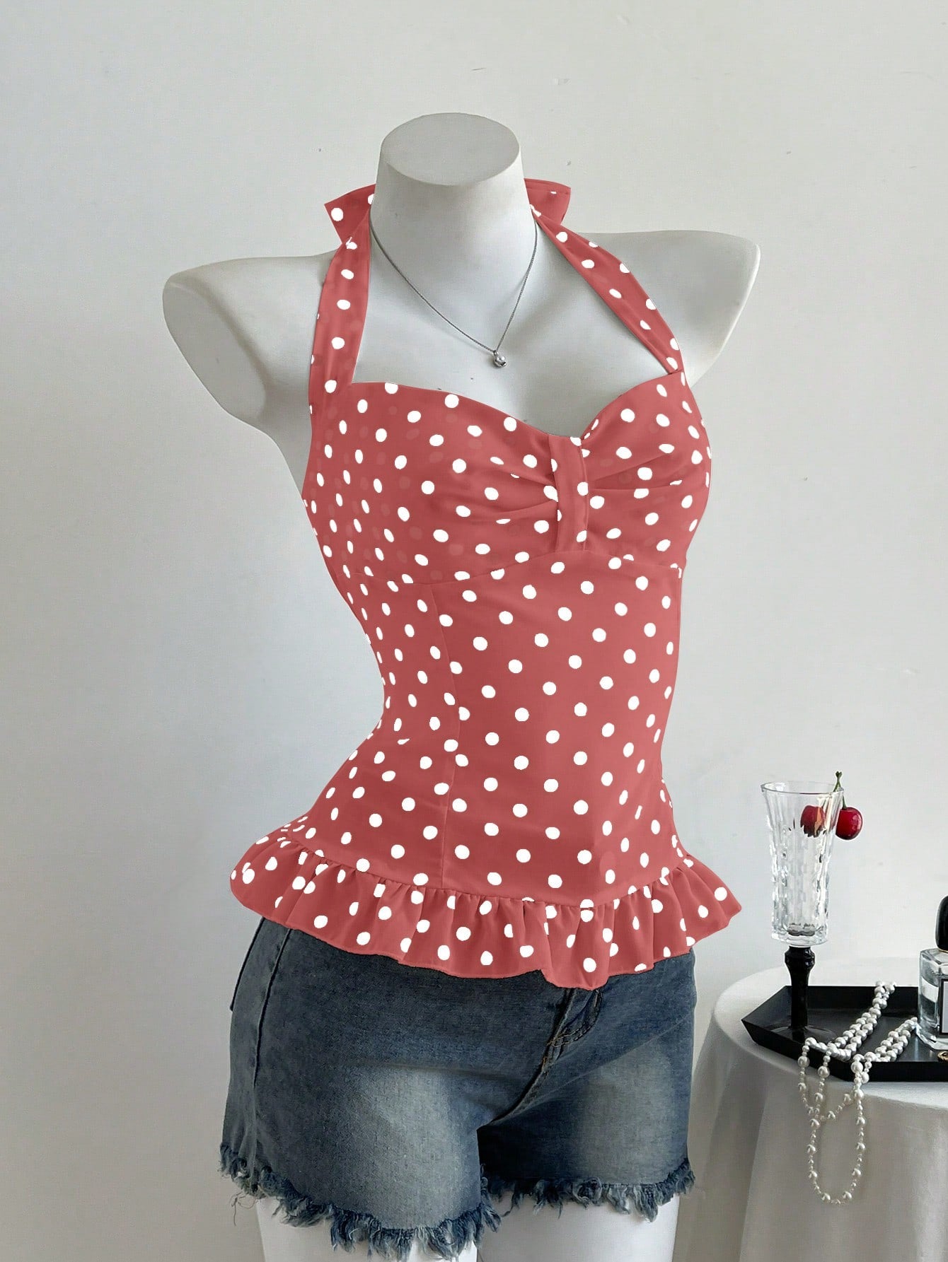 Women's polka dot halter camisole with bow bust detail, ruched and shirred design, slim crop fit, and flared ruffle hem.
