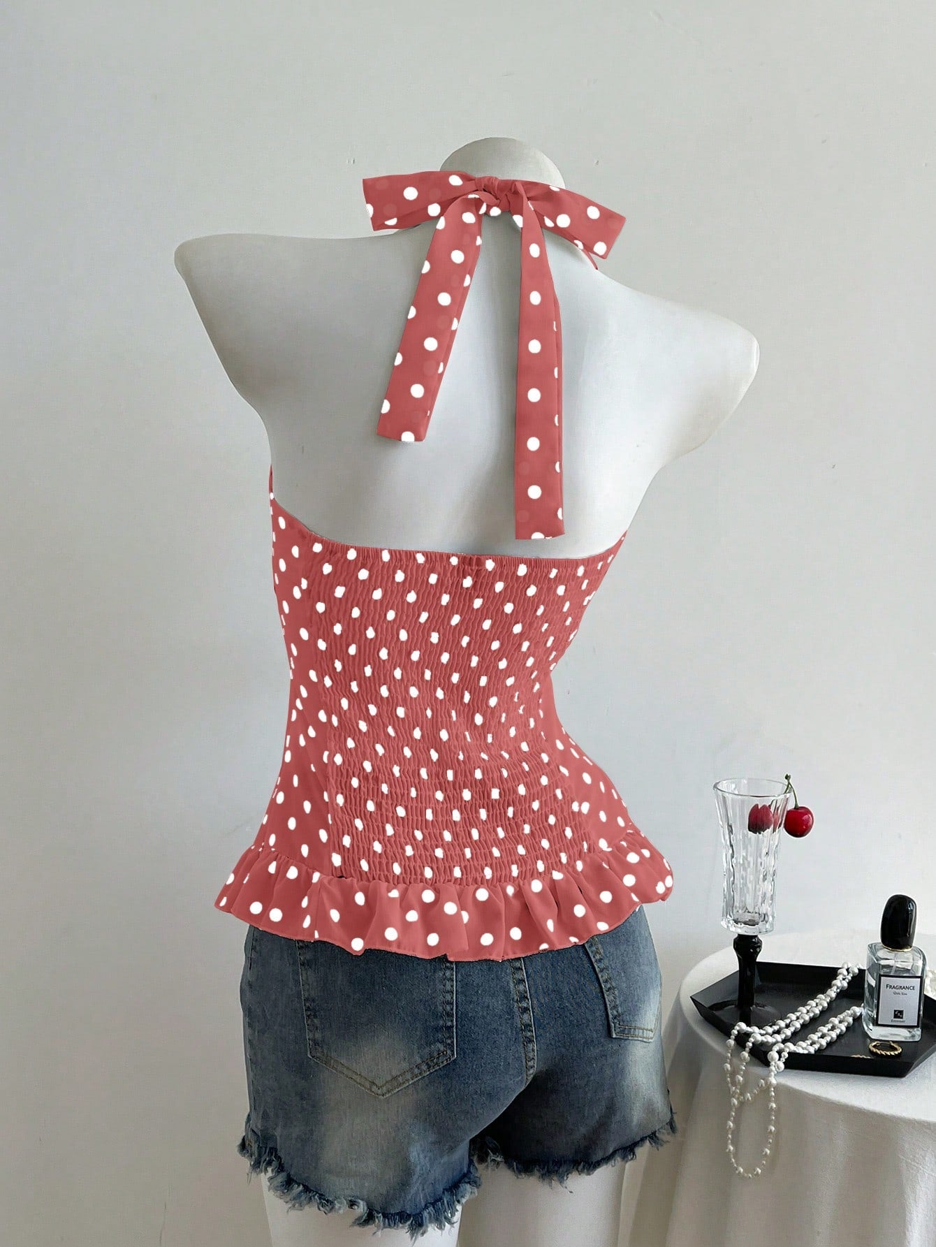 Women's polka dot halter camisole with bow bust detail, ruched and shirred design, slim crop fit, and flared ruffle hem.