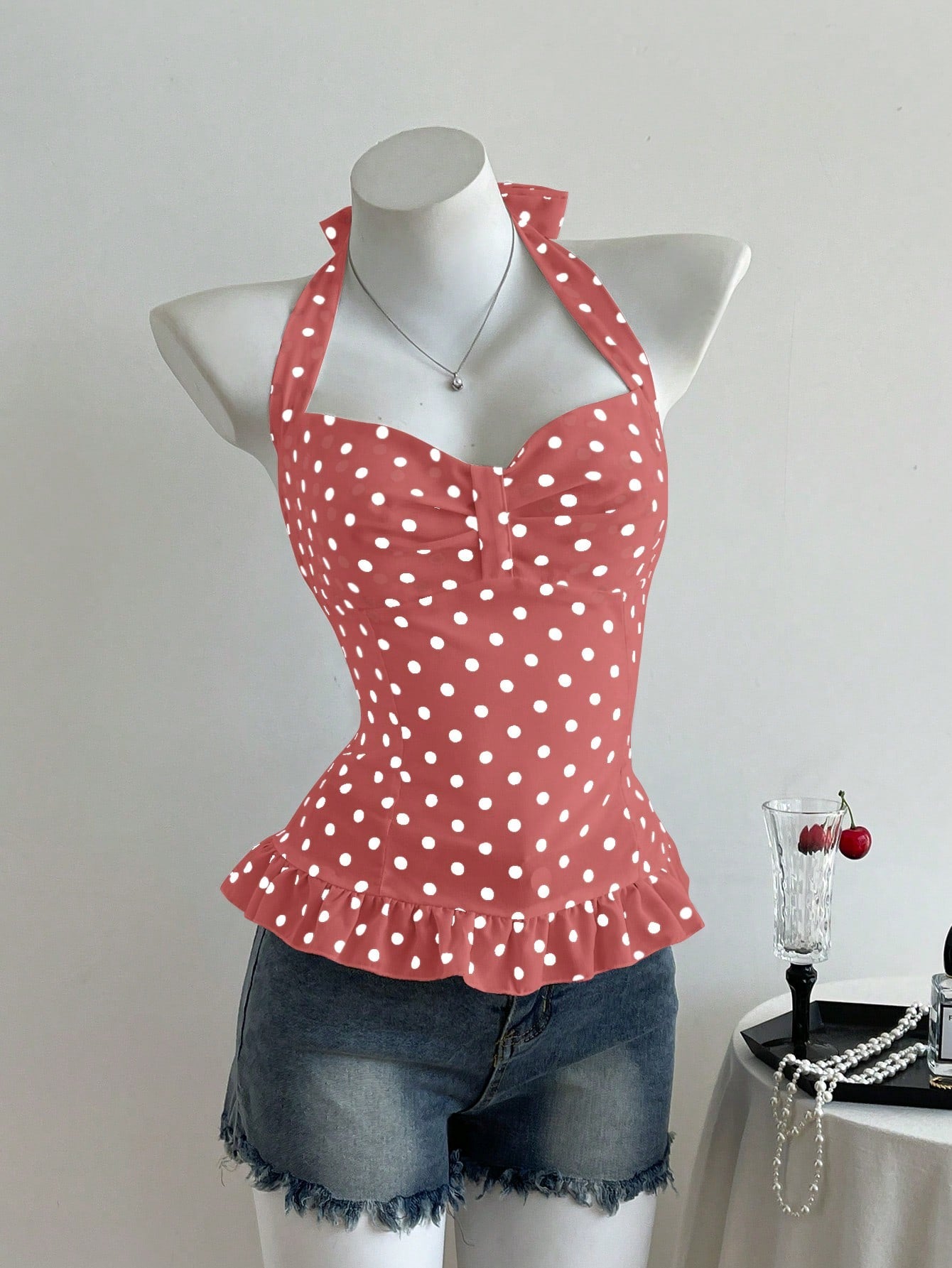 Women's polka dot halter camisole with bow bust detail, ruched and shirred design, slim crop fit, and flared ruffle hem.