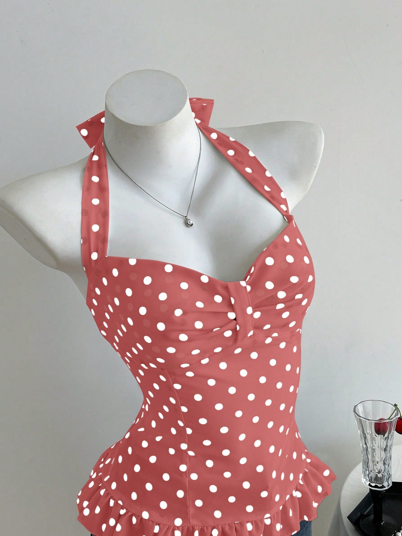 Women's polka dot halter camisole with bow bust detail, ruched and shirred design, slim crop fit, and flared ruffle hem.