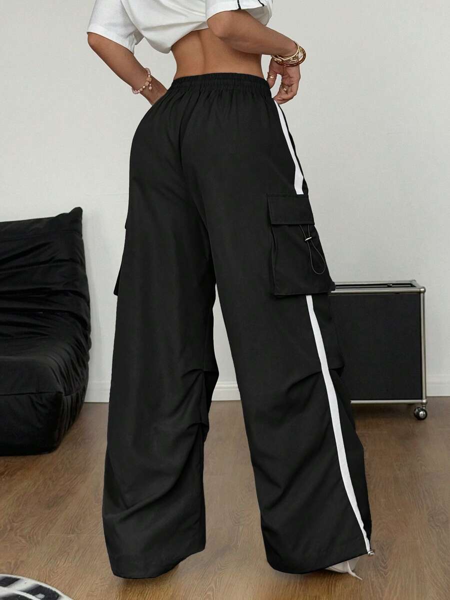 Dark grey loose fit parachute cargo pants for women featuring an elastic drawstring waistband and functional flap side pockets.