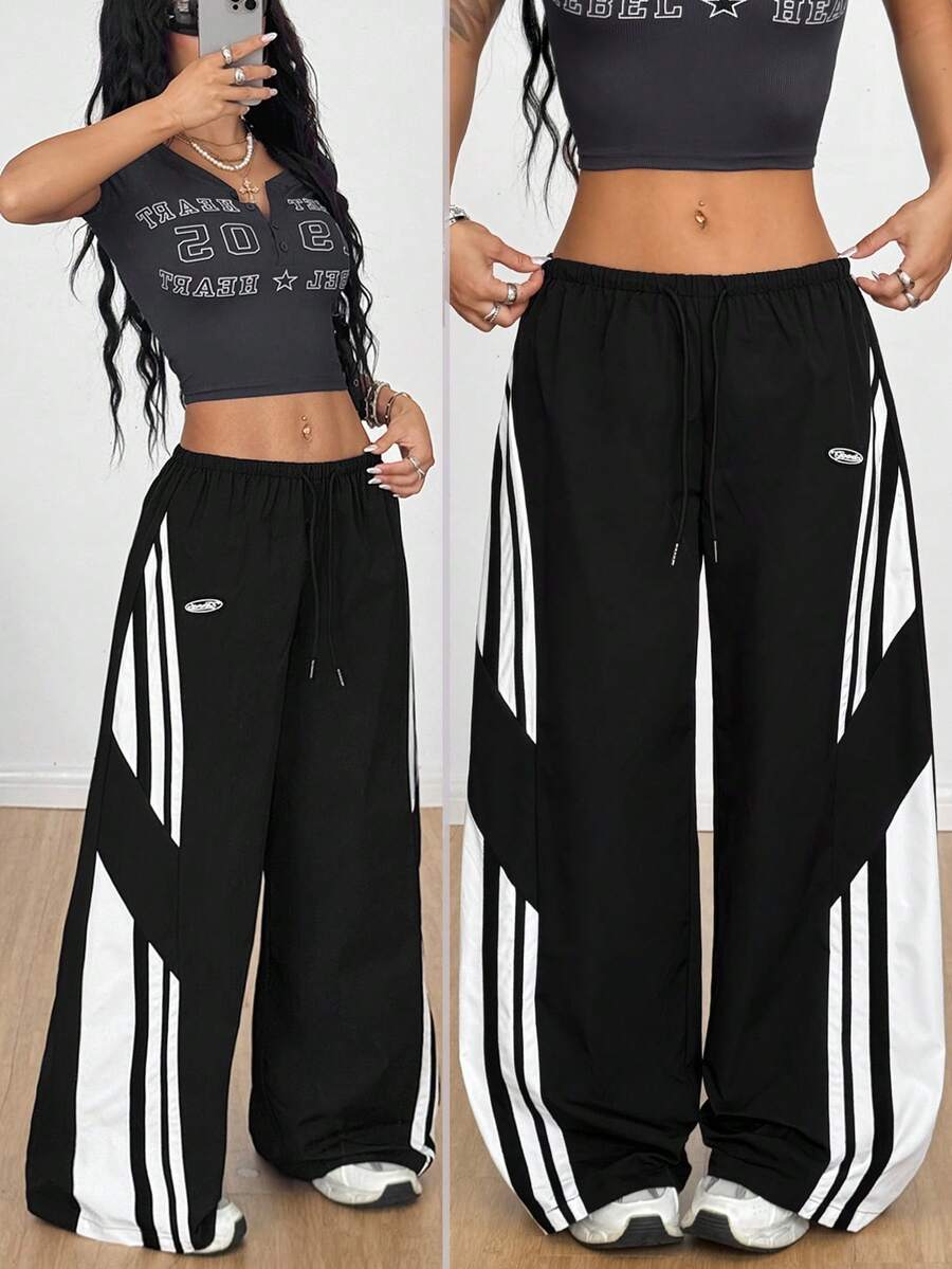 Women's wide leg parachute pants featuring an army green color-blocked design with side stripes and an adjustable drawstring waist.