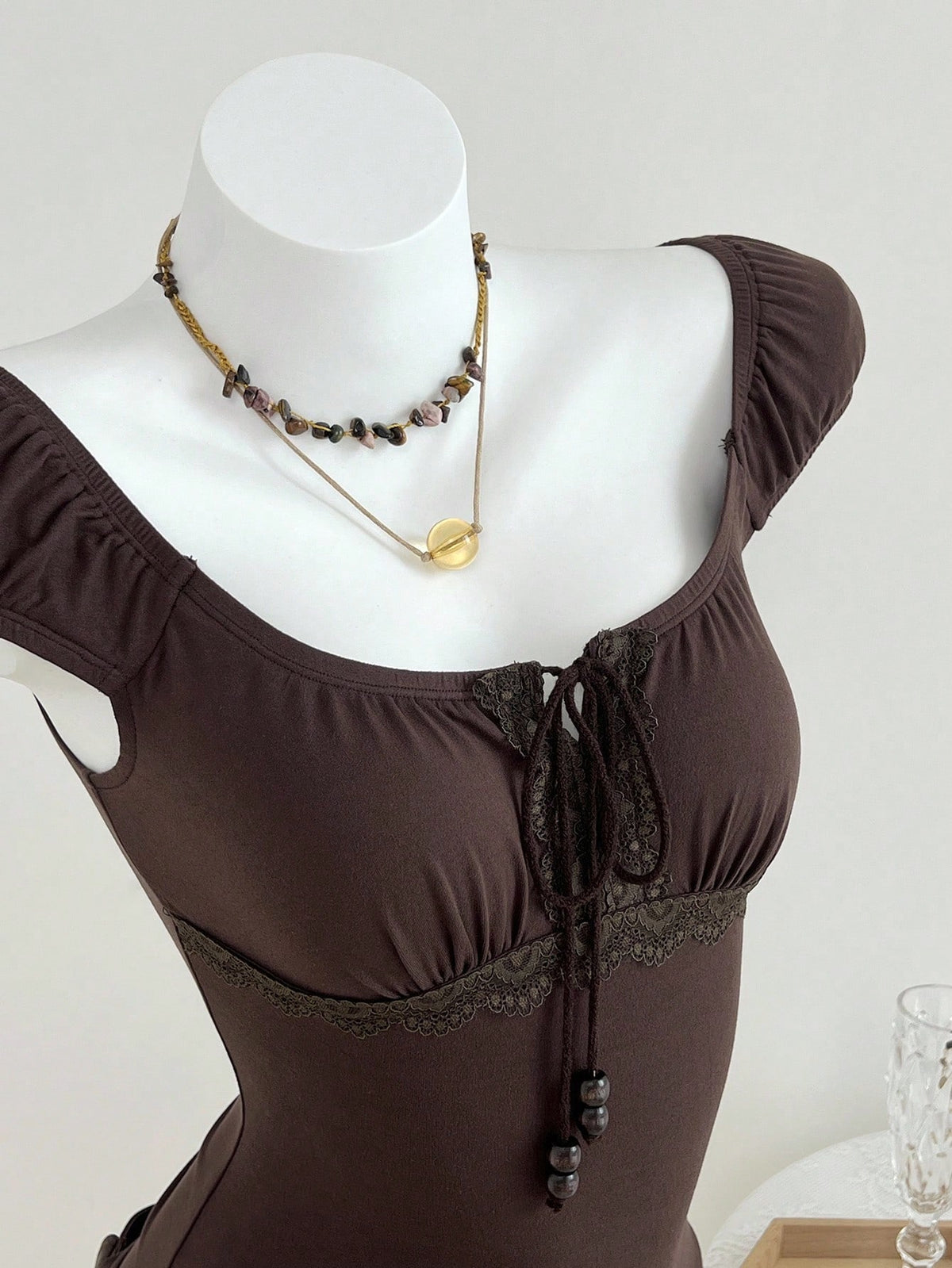 Women's brown slim-fit t-shirt with contrast lace trim, knot detail, scoop neck, and raglan cap sleeves.