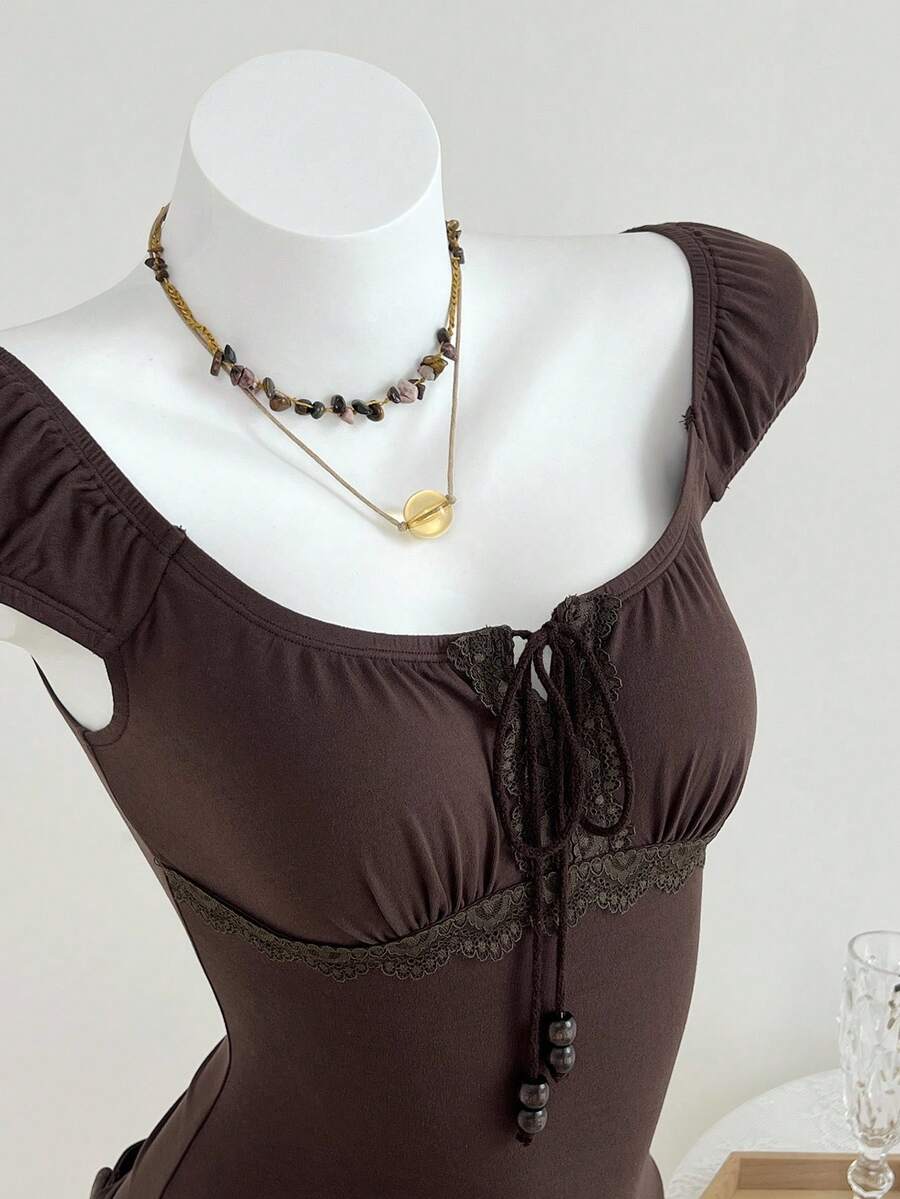 Women's brown slim-fit t-shirt with contrast lace trim, knot detail, scoop neck, and raglan cap sleeves.