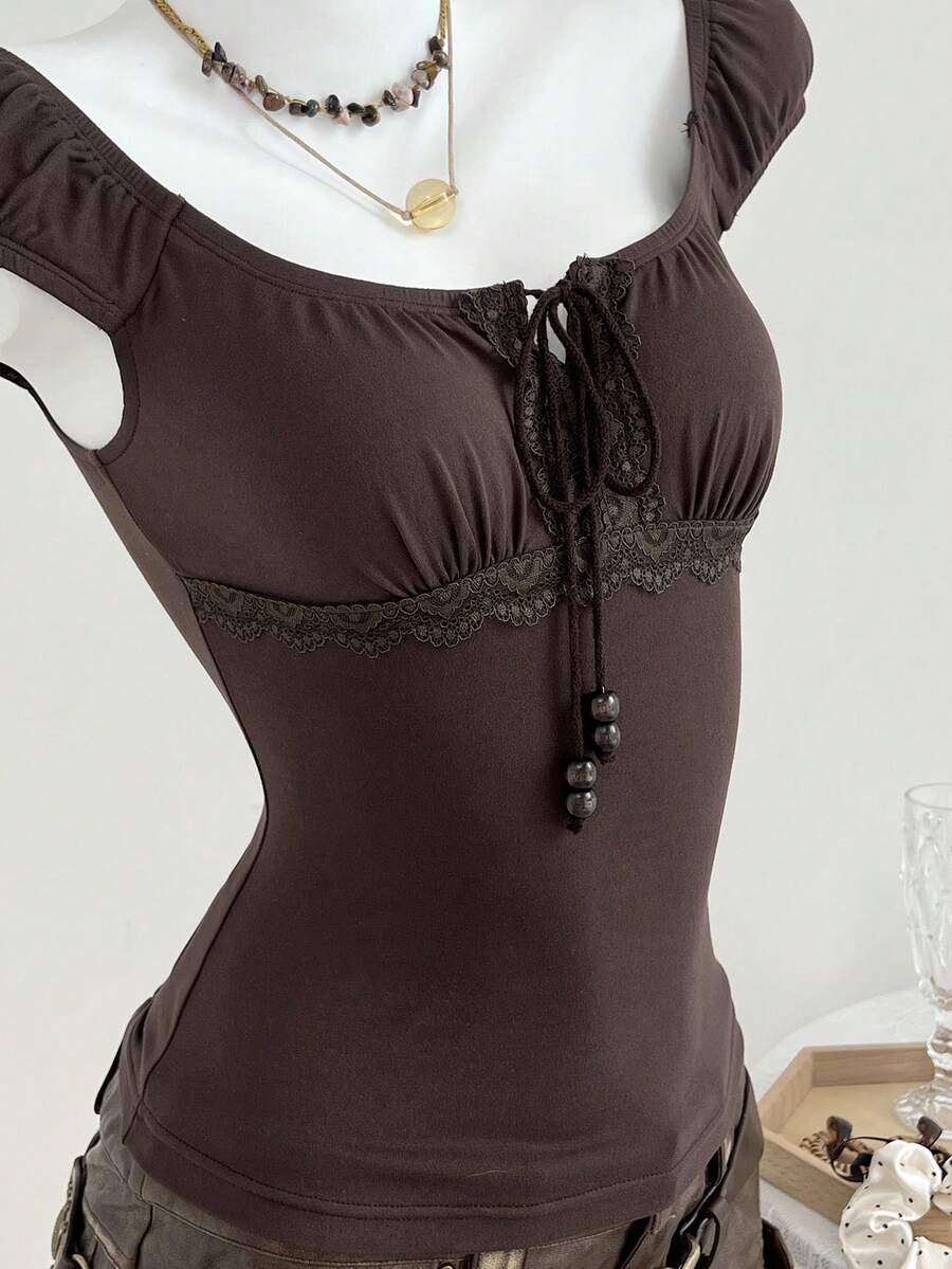 Women's brown slim-fit t-shirt with contrast lace trim, knot detail, scoop neck, and raglan cap sleeves.