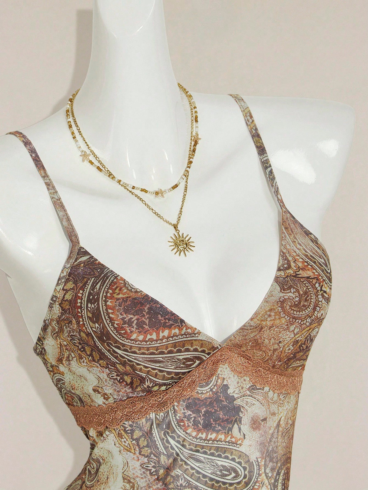 Women's graphic print camisole top featuring thin spaghetti straps, a backless cut, and an asymmetrical hem.