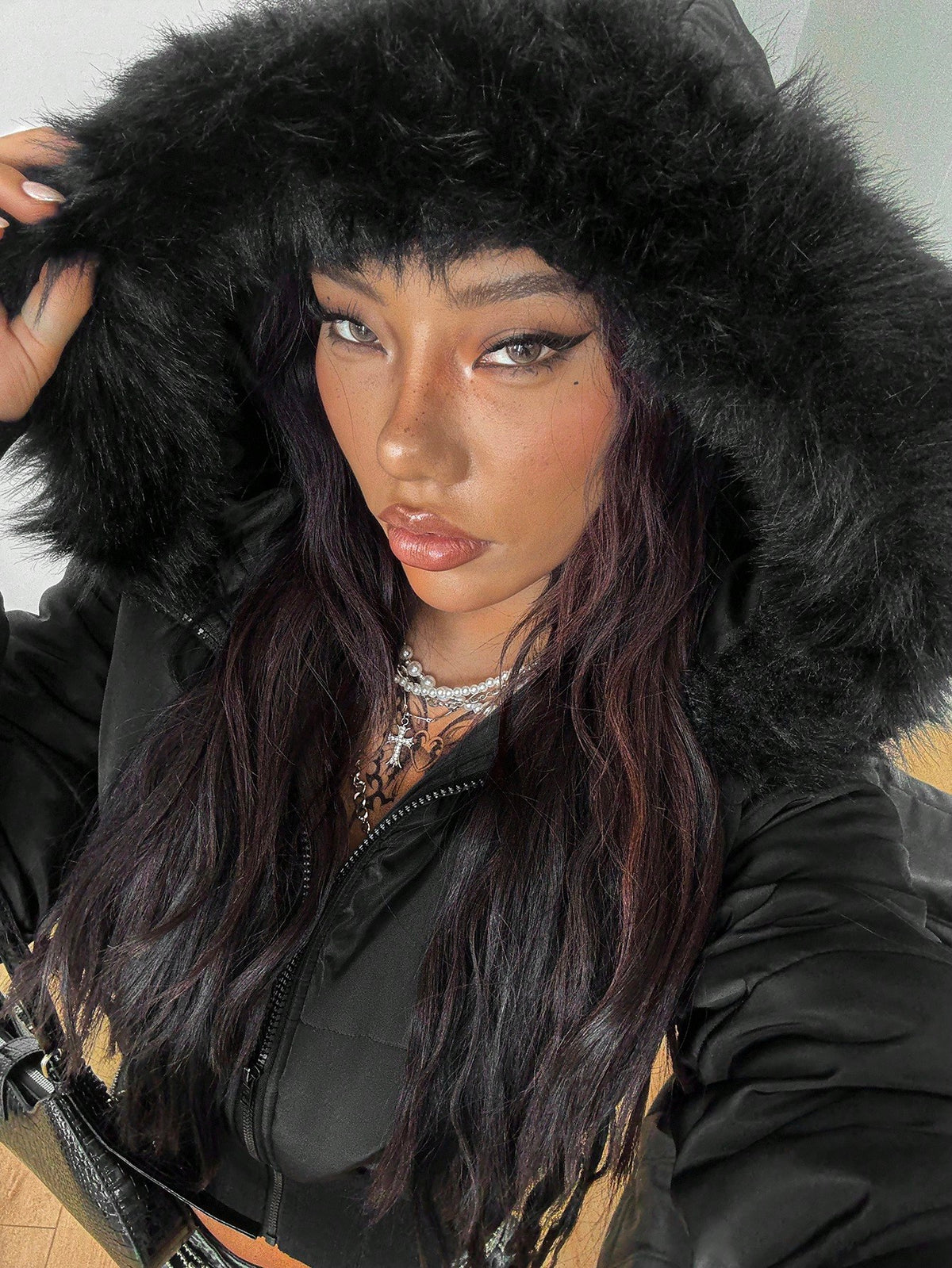 Women's brown cropped puffer jacket featuring a faux fur trimmed hood, front zipper, and ribbed hem.