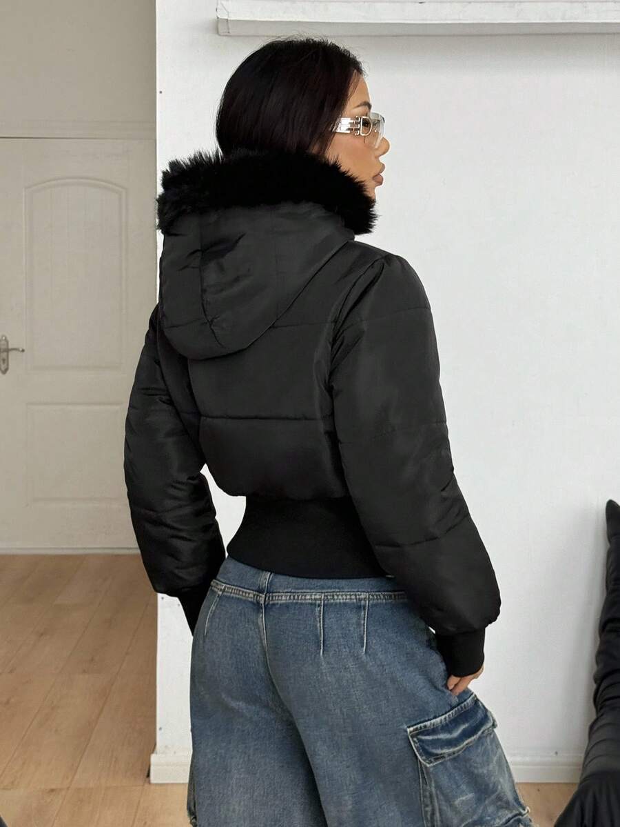 Women's brown cropped puffer jacket featuring a faux fur trimmed hood, front zipper, and ribbed hem.