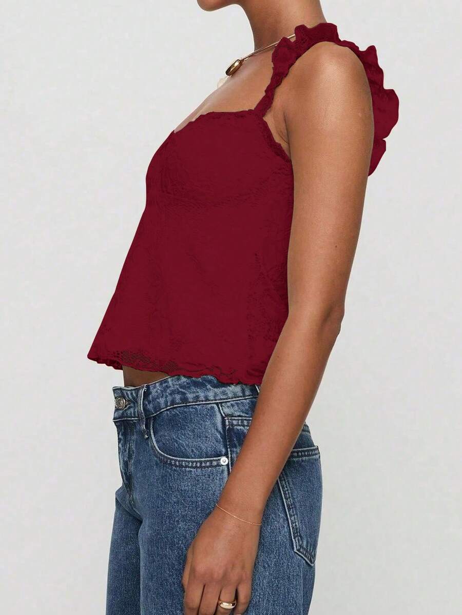 Sleeveless cami tank top featuring contrast lace patchwork design, ruffle spaghetti straps, and bow decor.