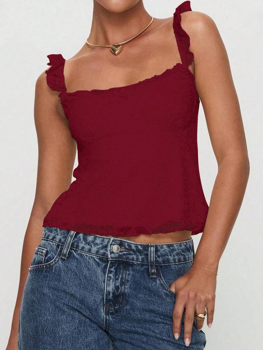 Sleeveless cami tank top featuring contrast lace patchwork design, ruffle spaghetti straps, and bow decor.
