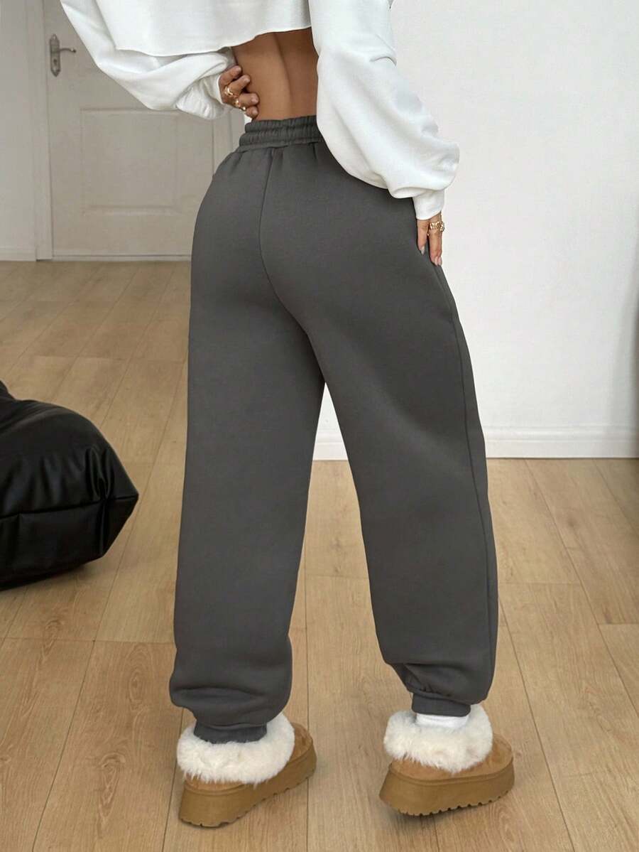 Women's casual grey jogger pants featuring a loose fit, mid-rise cut, and adjustable drawstring waistband.