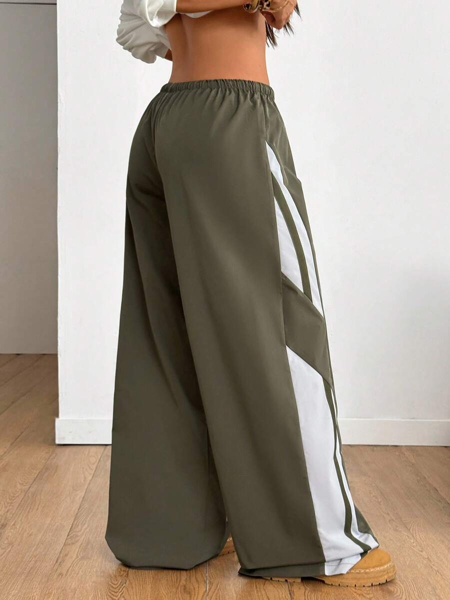 Women's wide leg parachute pants featuring an army green color-blocked design with side stripes and an adjustable drawstring waist.