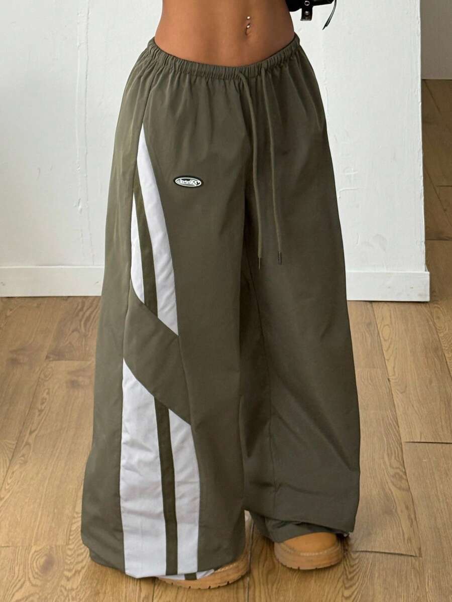 Women's wide leg parachute pants featuring an army green color-blocked design with side stripes and an adjustable drawstring waist.