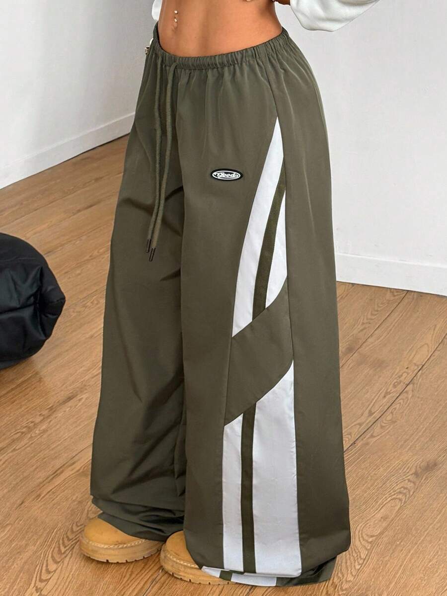 Women's wide leg parachute pants featuring an army green color-blocked design with side stripes and an adjustable drawstring waist.