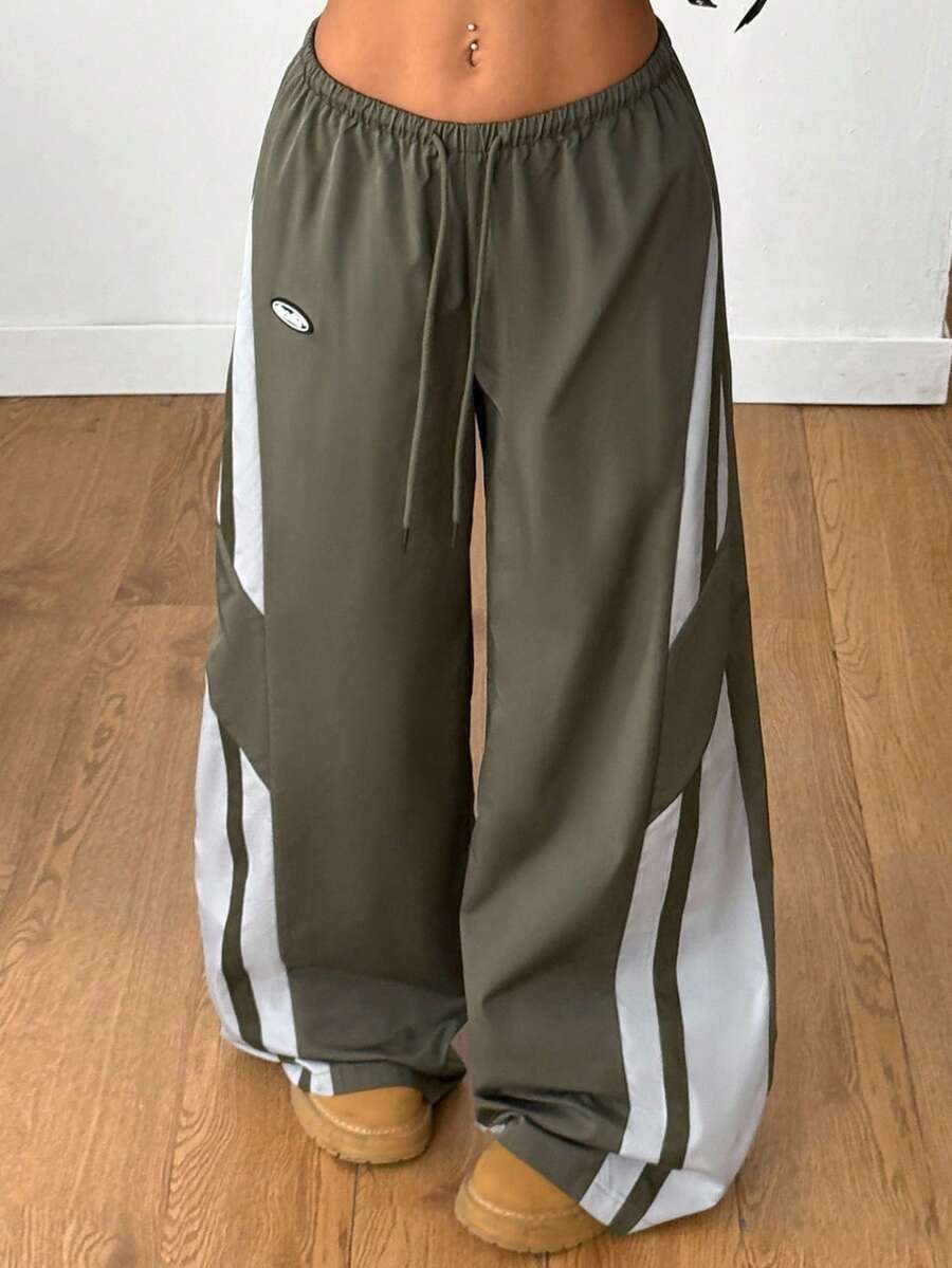 Women's wide leg parachute pants featuring an army green color-blocked design with side stripes and an adjustable drawstring waist.