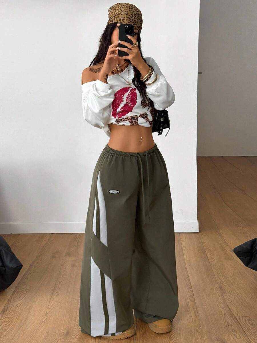 Women's wide leg parachute pants featuring an army green color-blocked design with side stripes and an adjustable drawstring waist.