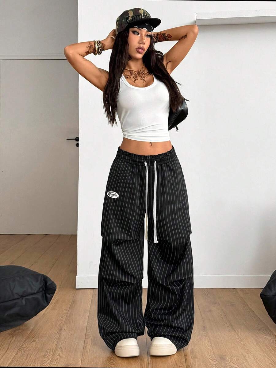 Women's black and white striped wide leg pants featuring an elastic drawstring waistband, side pockets, and a loose straight leg fit.