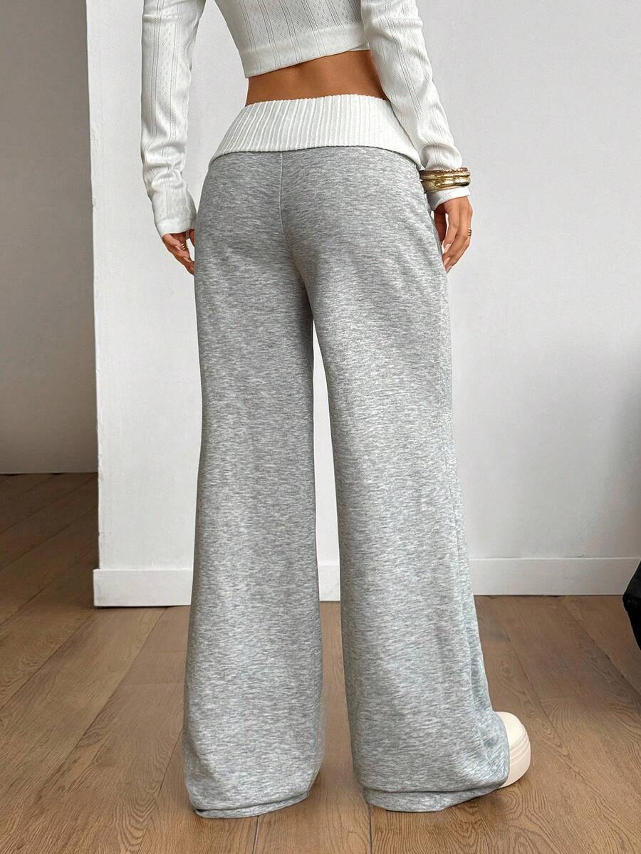 Women's wide leg flare sweatpants featuring a black and white colorblock contrast fold waistband and side stripe details.