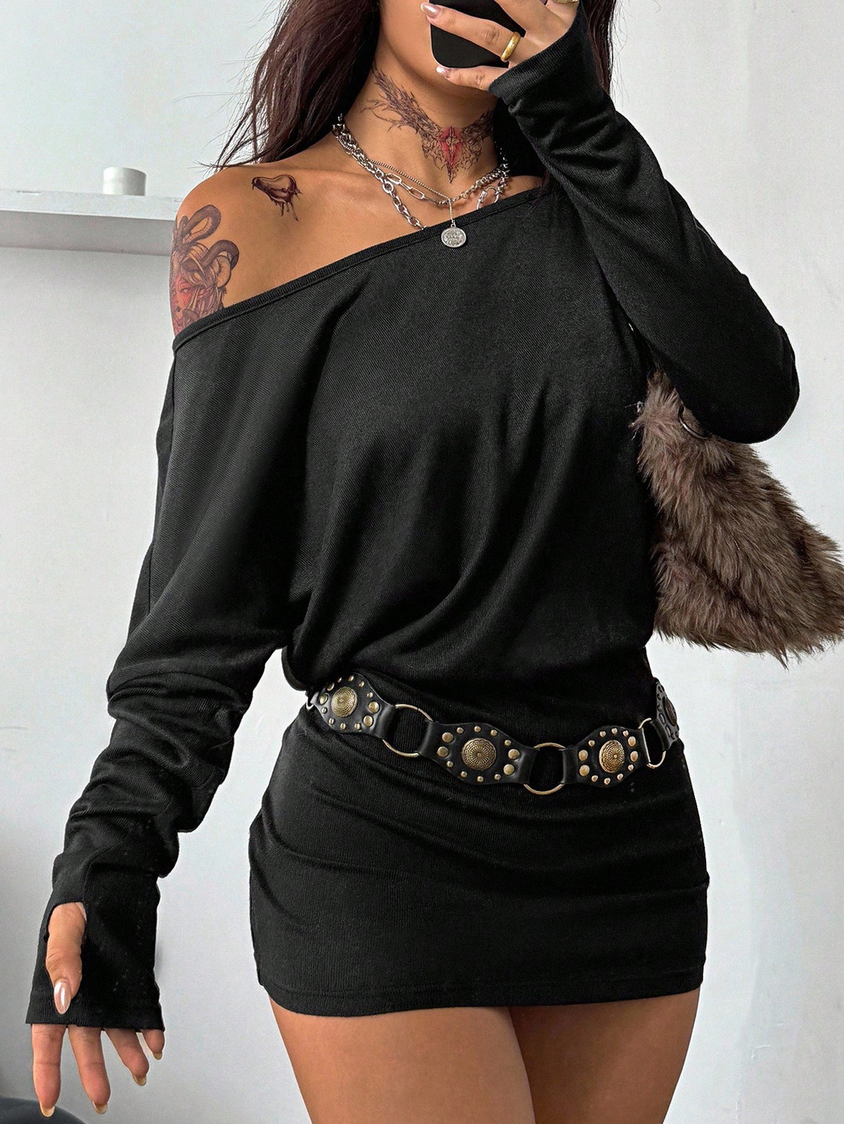 Women's long sleeve bodycon mini dress in black knitted fabric with an asymmetrical neckline and ruched accents.
