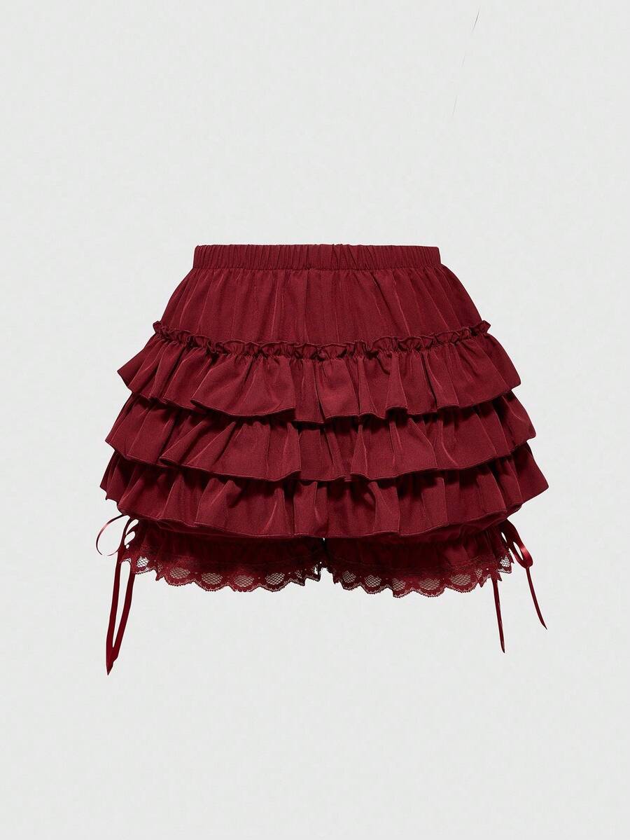 Women's tiered ruffle skort shorts featuring an elastic mid waist with front tie knot detail in woven fabric.