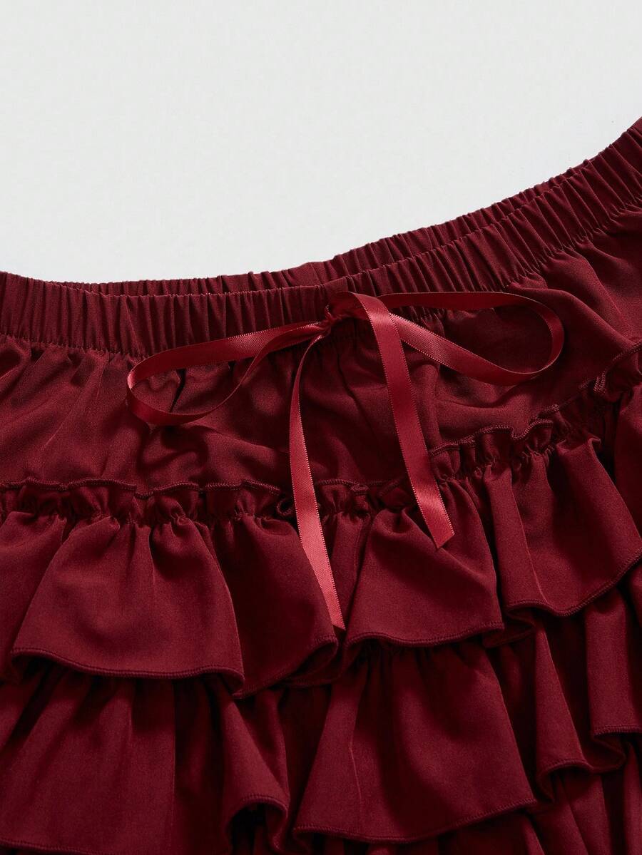 Women's tiered ruffle skort shorts featuring an elastic mid waist with front tie knot detail in woven fabric.