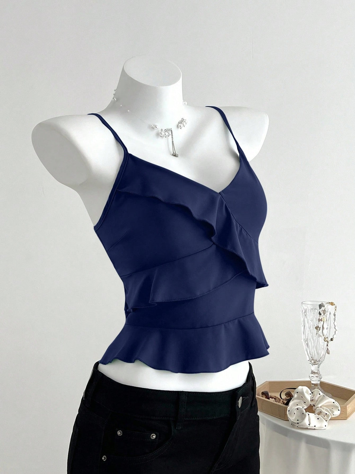 Women's solid color camisole top with thin spaghetti straps, tiered layers, and a flared ruffled hem.