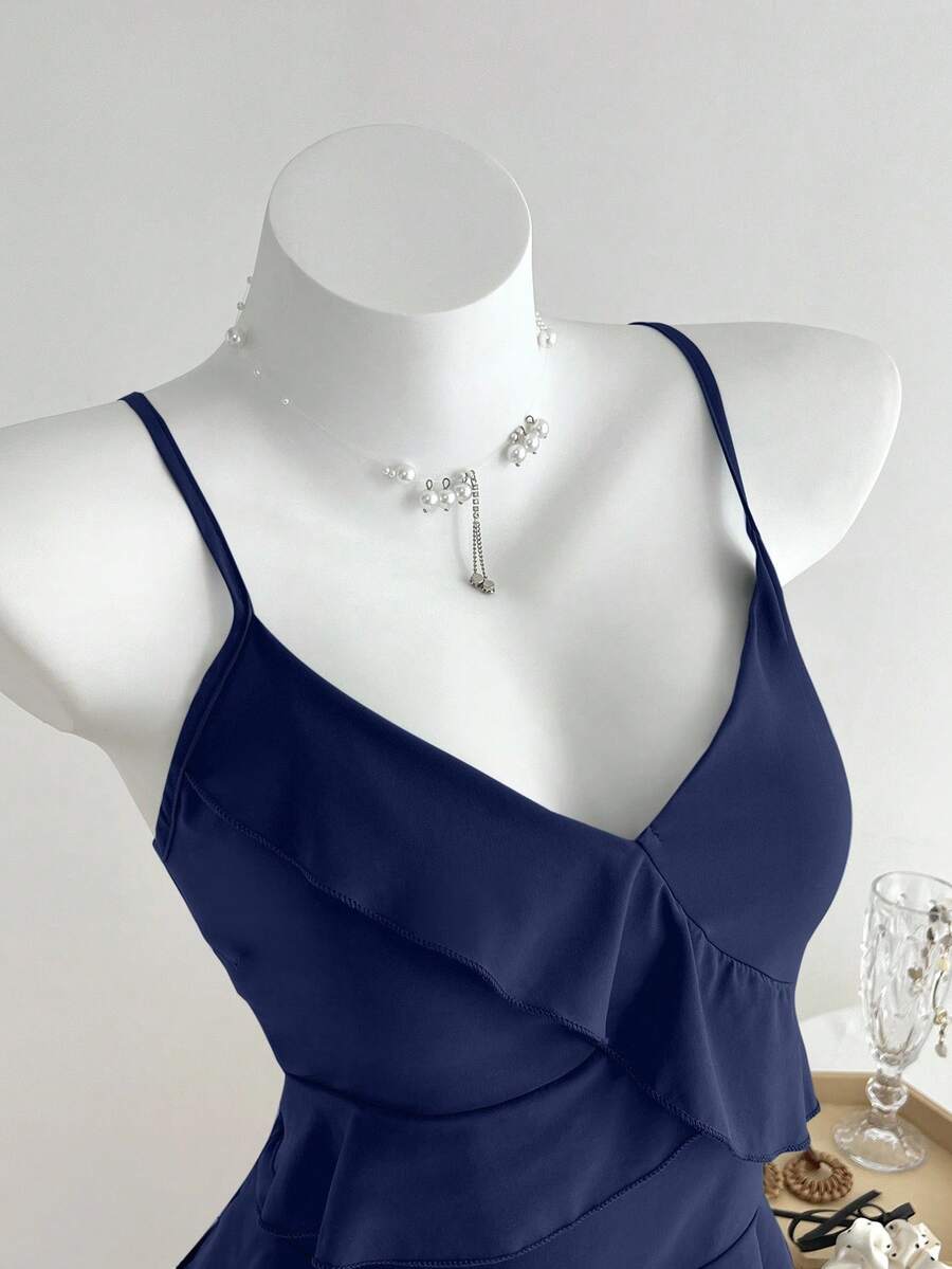Women's solid color camisole top with thin spaghetti straps, tiered layers, and a flared ruffled hem.