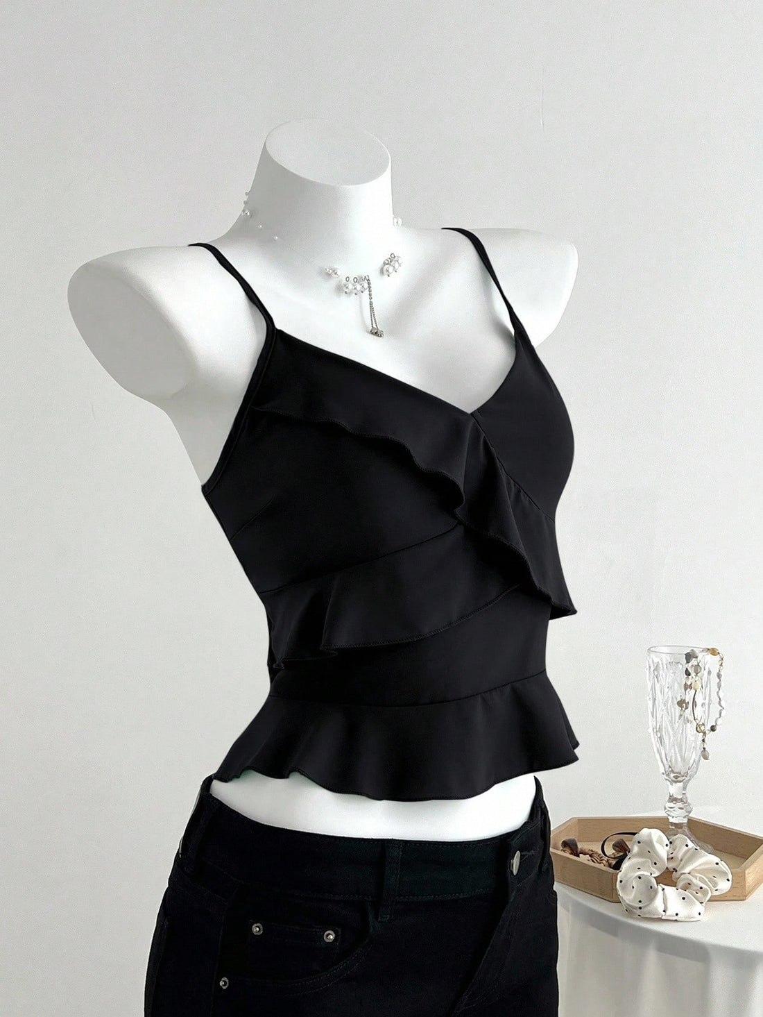 Women's solid color camisole top with thin spaghetti straps, tiered layers, and a flared ruffled hem.