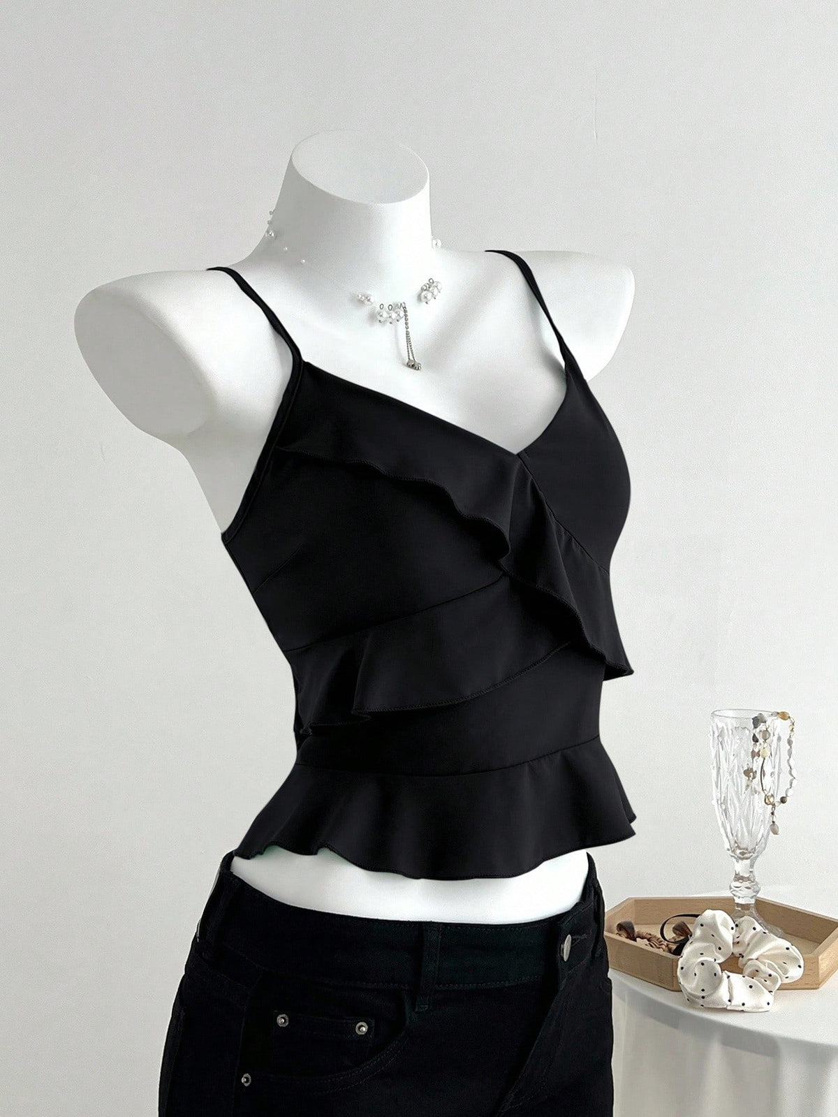 Women's solid color camisole top with thin spaghetti straps, tiered layers, and a flared ruffled hem.