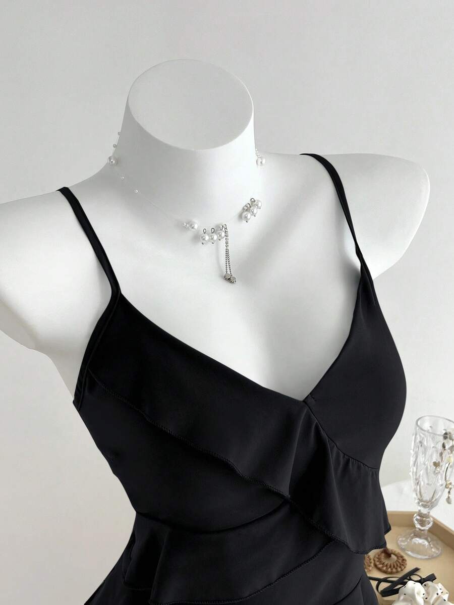 Women's solid color camisole top with thin spaghetti straps, tiered layers, and a flared ruffled hem.