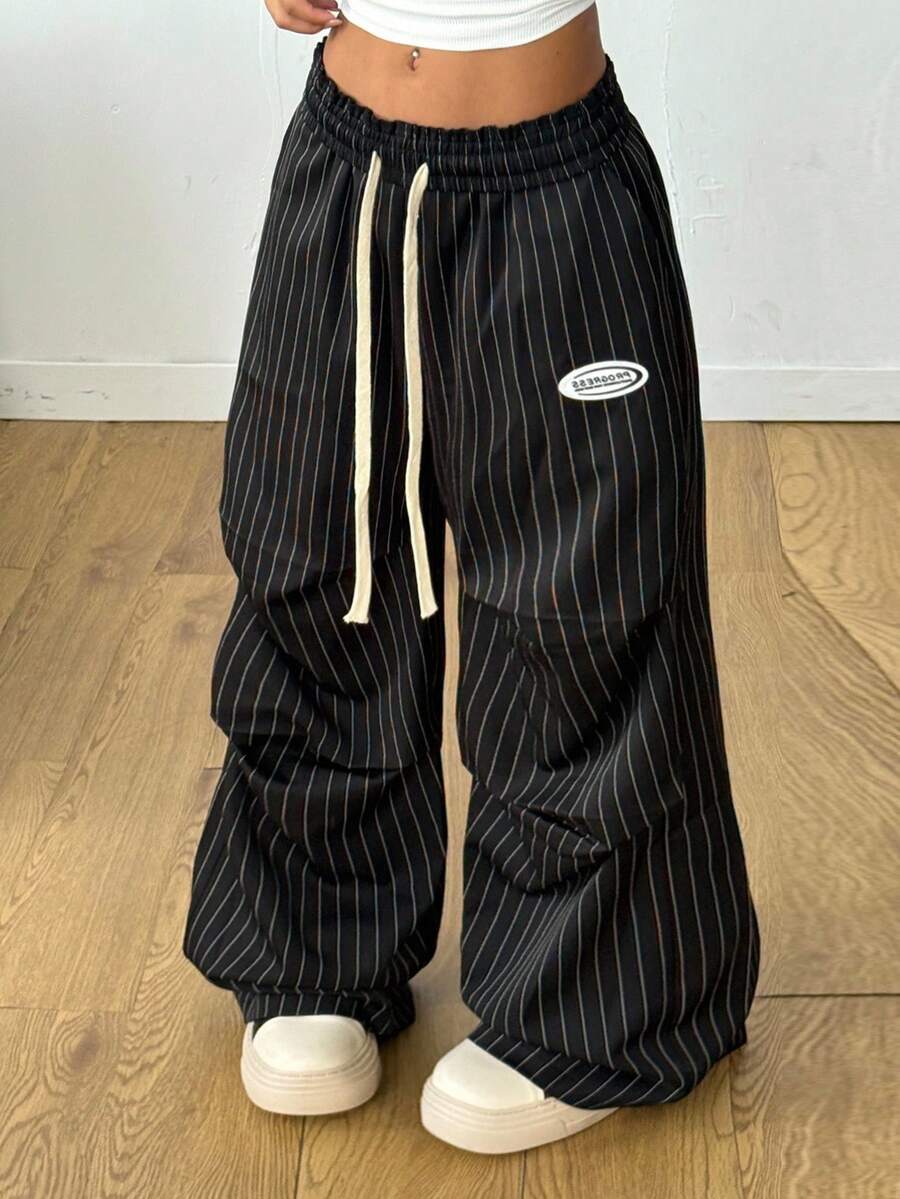 Women's black and white striped wide leg pants featuring an elastic drawstring waistband, side pockets, and a loose straight leg fit.
