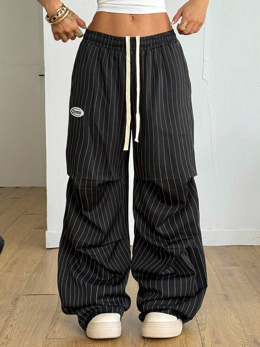 Women's black and white striped wide leg pants featuring an elastic drawstring waistband, side pockets, and a loose straight leg fit.