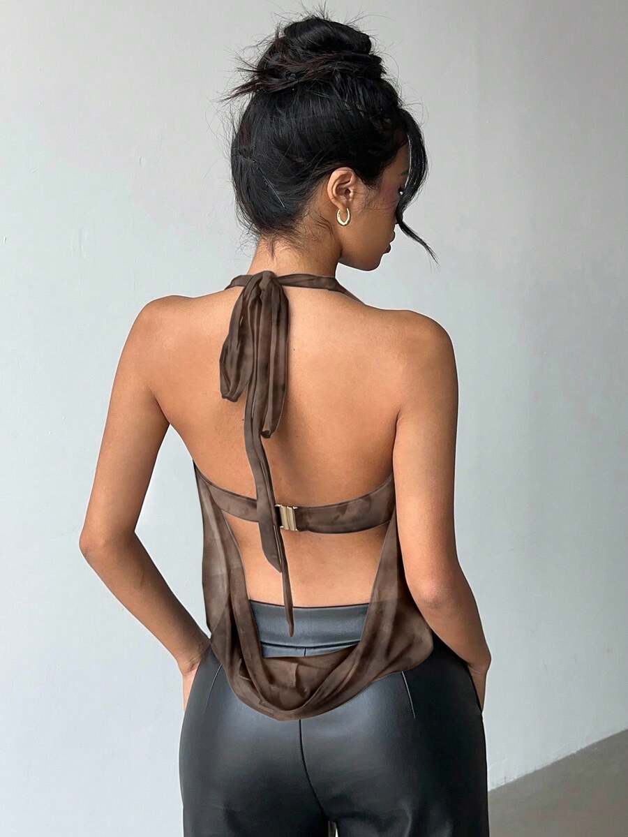 Brown and white polka dot semi-sheer halter camisole top with a plunging neckline, backless design, draped front, and metallic studded embellishments.