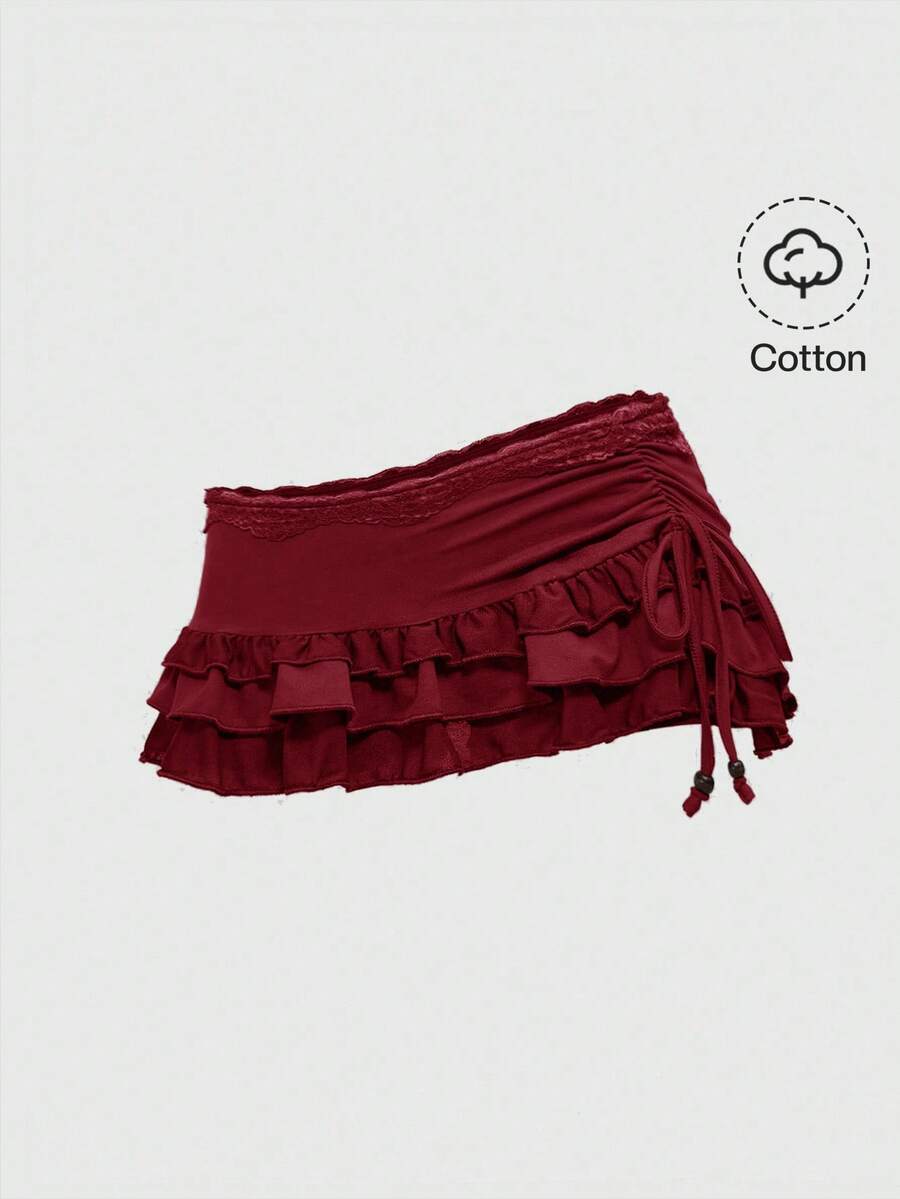 Women's black low-waist mini skirt with drawstring tie, ruched details, lace trim, layered ruffle hem, and asymmetric styling