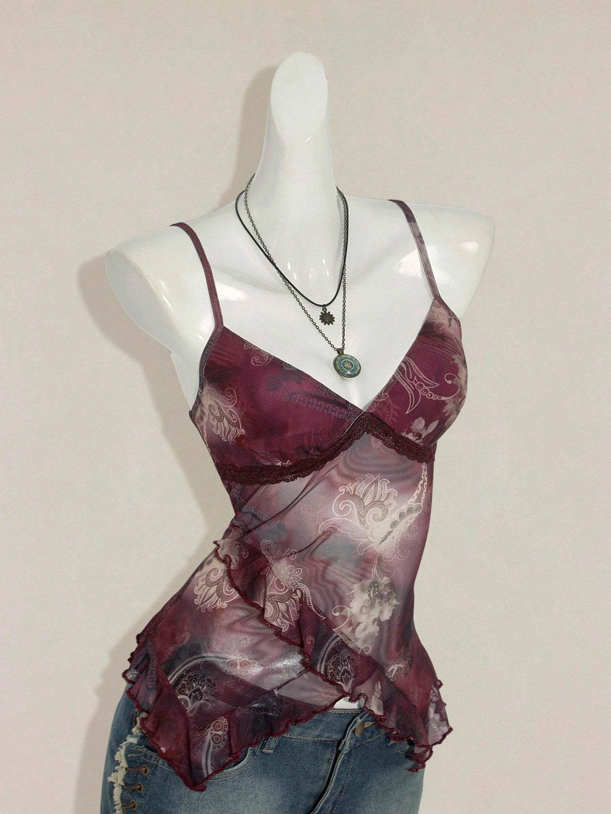Women's graphic print camisole top featuring thin spaghetti straps, a backless cut, and an asymmetrical hem.