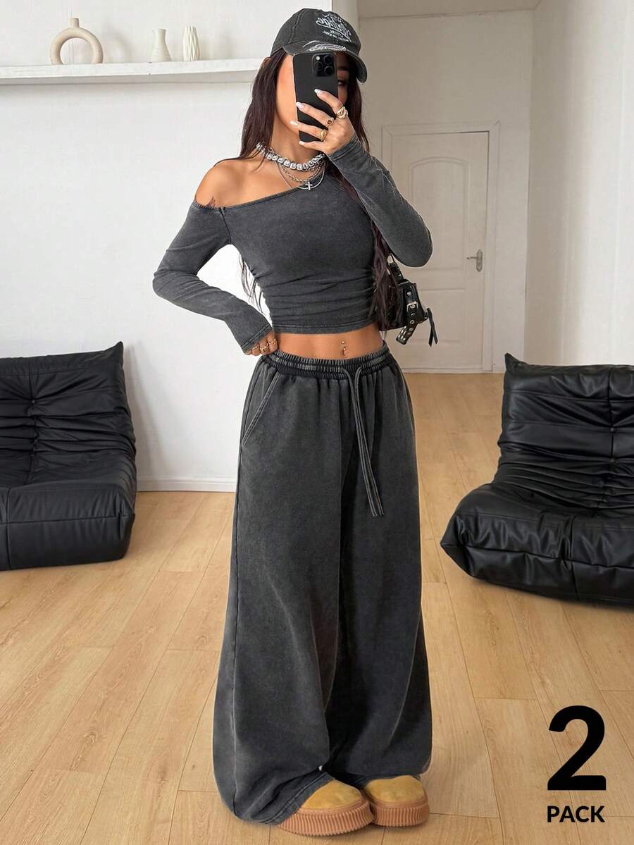 Women's two-piece knit lounge set featuring a black long sleeve asymmetrical crop top and matching high-waisted wide leg sweatpants.