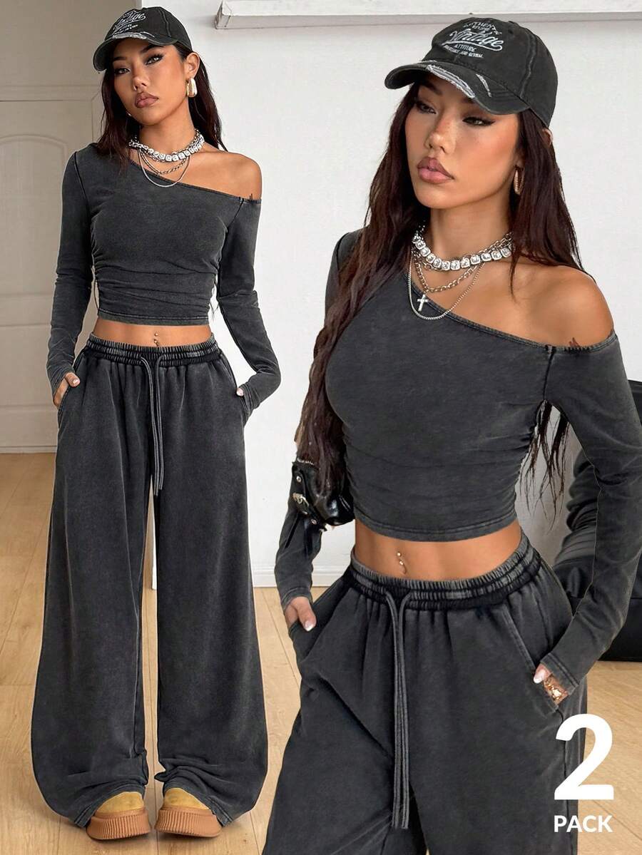 Women's two-piece knit lounge set featuring a black long sleeve asymmetrical crop top and matching high-waisted wide leg sweatpants.