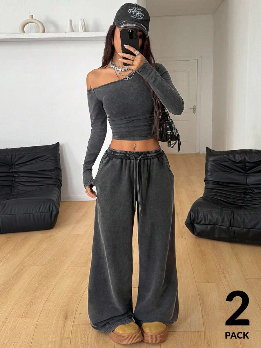 Women's two-piece knit lounge set featuring a black long sleeve asymmetrical crop top and matching high-waisted wide leg sweatpants.