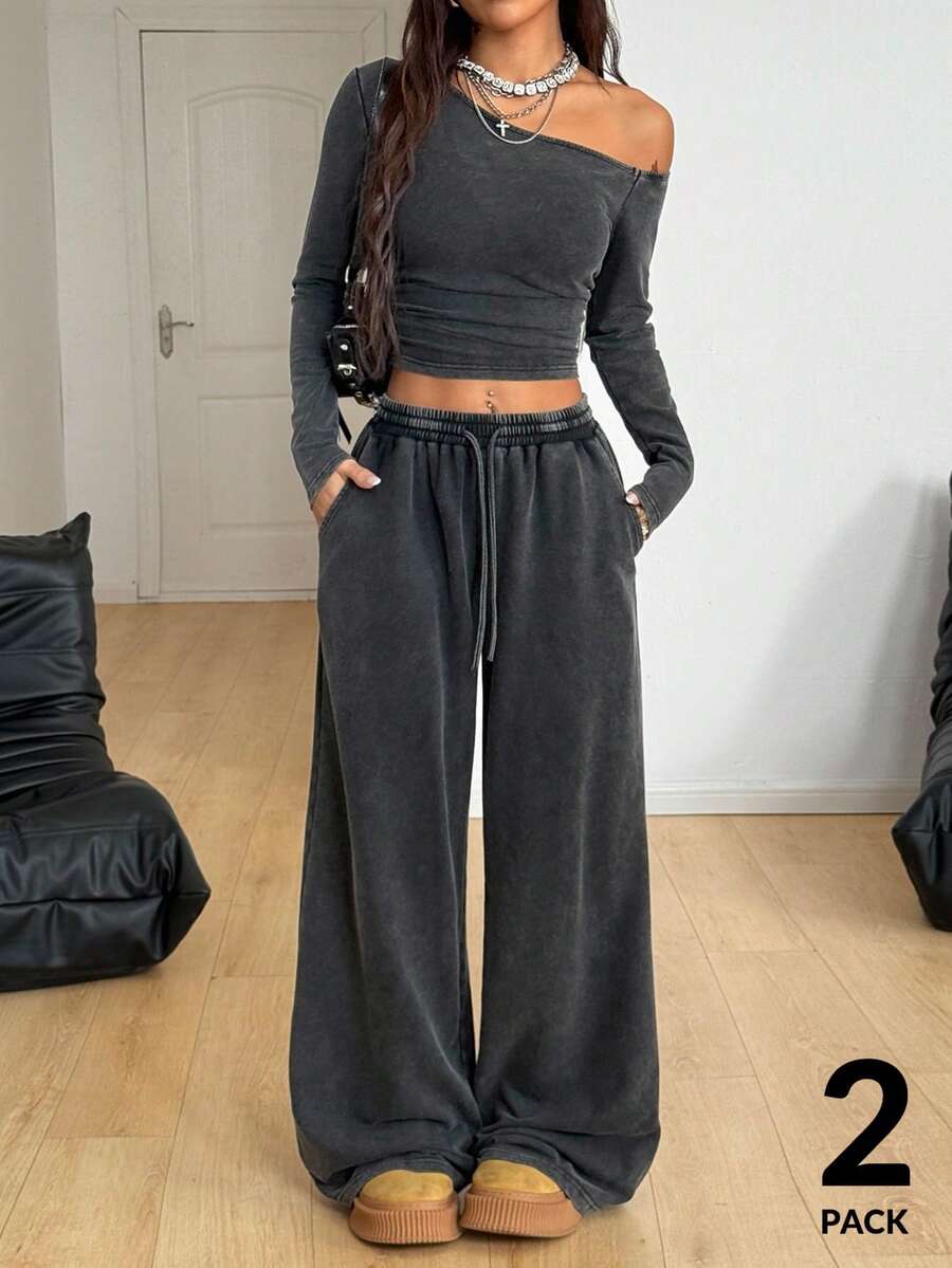 Women's two-piece knit lounge set featuring a black long sleeve asymmetrical crop top and matching high-waisted wide leg sweatpants.
