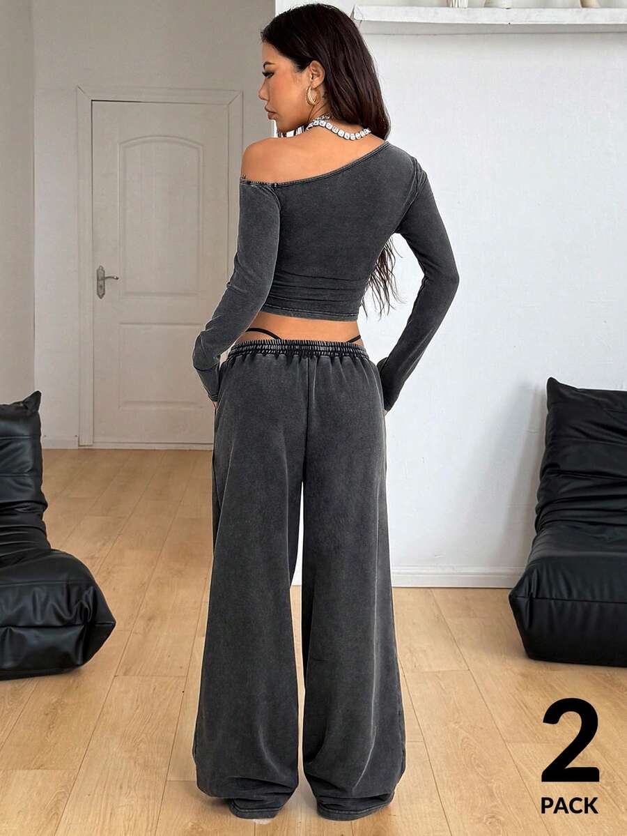 Women's two-piece knit lounge set featuring a black long sleeve asymmetrical crop top and matching high-waisted wide leg sweatpants.