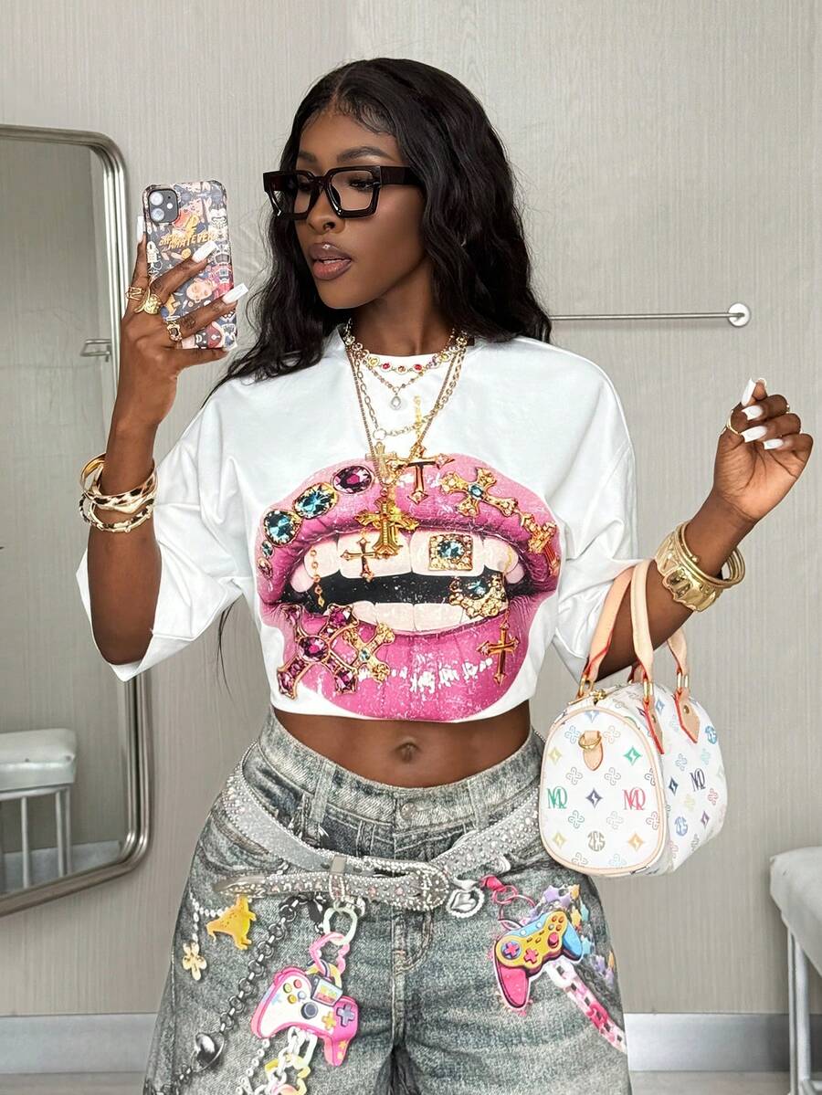 Front view of a women's black oversized crop t-shirt with pink lips graphic, round neckline, and short drop-shoulder sleeves.